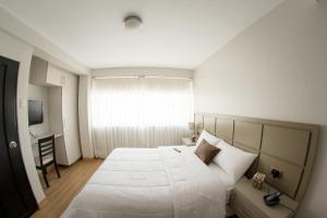 sypialnia z dużym białym łóżkiem i oknem w obiekcie Hotel Convencion w mieście Trujillo