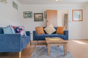 Sala de estar con 2 sofás azules y mesa de centro en Hosts on the Coast Escape on Esplanade, en Whitianga