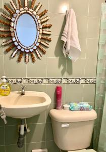a bathroom with a sink and a toilet and a mirror at La Casa de Tía Ana in Ríohacha