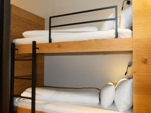 Cette chambre comprend 4 lits superposés avec des oreillers blancs. dans l'établissement My Heimat 1495 Arlberg, à Schröcken