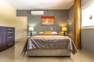 a bedroom with a large bed with two lamps on it at Juanedu Suites in Oranjestad