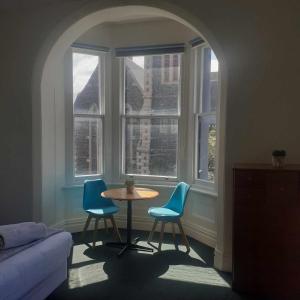 a living room with a table and two blue chairs at Hope Street Apartments in Dunedin