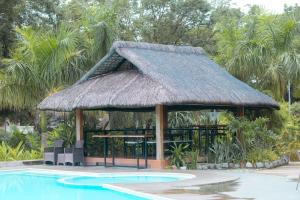 einen Pavillon mit einem Grasdach neben einem Pool in der Unterkunft Bellagio Hills Hotel and Restaurant in Paoay