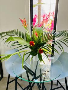un tavolo di vetro con un vaso con dei fiori sopra di Paradise Escape - Poolside Ground Floor - Sea Temple Resort and Spa a Port Douglas