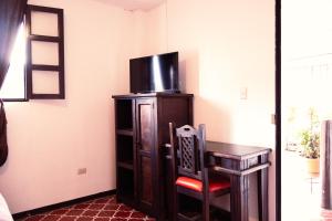 a room with a chair and a desk with a tv at Lar Antiqua Hotel in Quetzaltenango