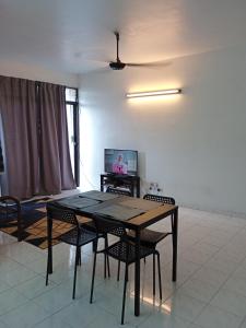 ein Esszimmer mit einem Tisch, Stühlen und einem TV in der Unterkunft Homestay Idaman Penang in Permatang Pauh