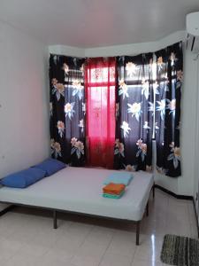 Bett in einem Zimmer mit 2 Fenstern mit Vorhängen in der Unterkunft Homestay Idaman Penang in Permatang Pauh