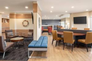 a waiting room with a blue bench and tables and chairs at TownePlace Suites by Marriott Janesville in Janesville