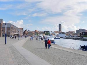 a group of people walking on a sidewalk next to a river at Ohlerich Speicher App_ 23 in Wismar