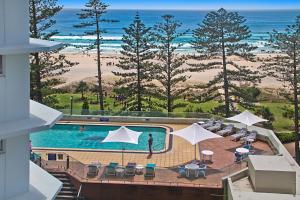 una piscina con sillas y sombrillas y el océano en Ocean Plaza Unit 835 en Gold Coast