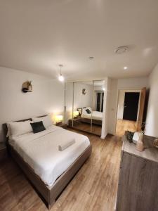 una camera da letto con un grande letto bianco e uno specchio di The maud luxury garden a Londra