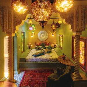 a bedroom with a large bed in a room with chandeliers at Riad Persephone in Marrakesh