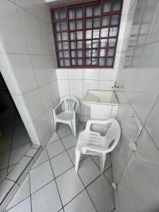 a white bathroom with a sink and a chair at Quarto Laurinda 3 in Guararema