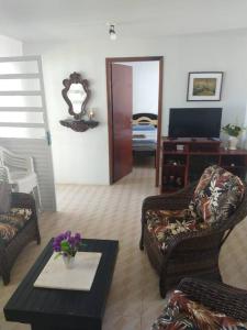 a living room with chairs and a table and a tv at Casa Aconchegante Frente ao Mar Guaratuba in Guaratuba