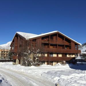 een groot houten gebouw met sneeuw op de grond bij Résidence Chalet d'Or by Leavetown Vacations in Les Deux Alpes
