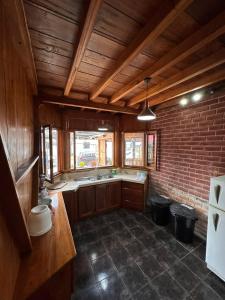 a kitchen with wooden ceilings and a brick wall at TONYs HOUSE MINDO in Mindo