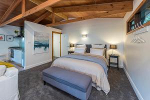 a bedroom with a large bed with a blue stool at Crabapple Cabin in Bowral