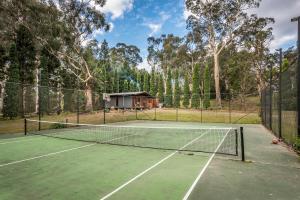 a tennis court with a house in the background at Crabapple Cabin in Bowral