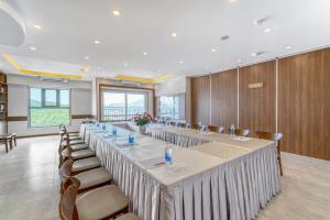 TK Nha Trang Hotel في نها ترانغ: قاعة اجتماعات كبيرة مع طاولة وكراسي طويلة