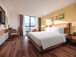 a hotel room with a large bed and a desk at Nesta Hotel & Spa in Hanoi