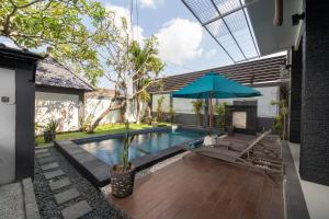 a swimming pool with a blue umbrella and a chair and a table at Villa Taurus in Seminyak
