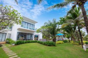 Biały dom z palmami przed nim w obiekcie D6 Aria Resort w mieście Vung Tau