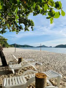 Attitude Resort Langkawi في بانتايْ سينانج: صف من الكراسي البيضاء تجلس على الشاطئ