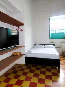 een slaapkamer met een bed en een flatscreen-tv bij Casa Orquidea Hostal Barichara in Barichara