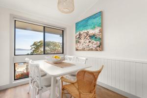 a white dining room with a white table and chairs at Dutchies Motel Nelson Bay & Dutchmans Beach Apartments in Nelson Bay