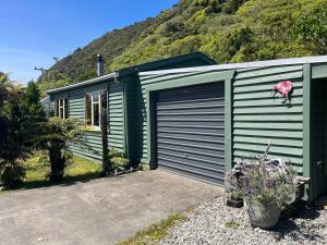 a green house with a garage and a mountain at Classic Kiwi bach in Granity
