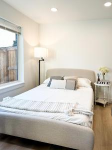 una camera da letto con un letto con lenzuola bianche e una finestra di New Comfort Cozy Modern Apartment Unit4 a Vancouver