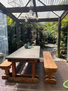 una mesa de picnic y dos bancos en una terraza de madera en Classic Kiwi bach en Granity