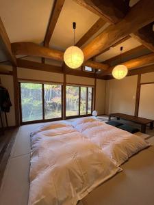 duże łóżko w środku pokoju z oknami w obiekcie Kyutei w mieście Minamioguni
