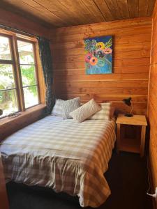 a bedroom with a bed in a wooden cabin at Classic Kiwi bach in Granity