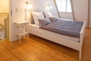a bedroom with a white bed and a wooden floor at Stadthaus Flensburg in Flensburg