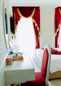 1 dormitorio con escritorio y silla roja en Dezon Hotel en Quy Nhon