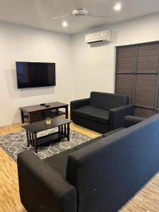 a living room with two couches and a flat screen tv at Garden Apartments in Nadi