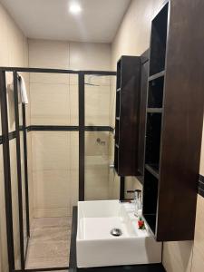 La salle de bains est pourvue d'un lavabo blanc et d'une douche. dans l'établissement Garden Apartments, à Nadi