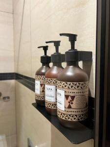 three bottles of soap sitting on a shelf in a bathroom at Garden Apartments in Nadi