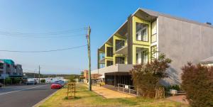a yellow building on the side of a street at Ishtar Apartment 1 Luxury Living Accommodation in Huskisson
