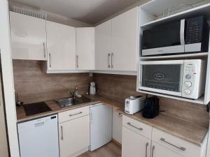 cocina con armarios blancos, microondas y fregadero en Appartement Les Deux Alpes, 2 pièces, 4 personnes - FR-1-516-210, en Les Deux Alpes