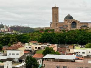 eine Stadt mit einem Uhrturm vor einem Gebäude in der Unterkunft Vista Privilegiada 5 minutos da Basílica in Aparecida