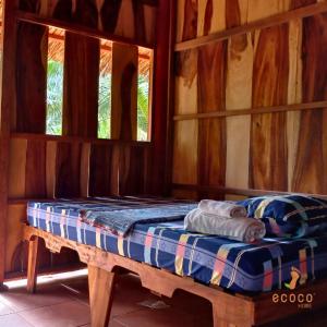 a bed in a wooden room with two windows at Ecoco Homestay Mekong in Ben Tre