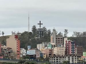 een stad met een kruis op een heuvel met gebouwen bij Vista Privilegiada 5 minutos da Basílica in Aparecida