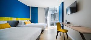 a hotel room with two beds and a desk and a tv at Hotel Tranz in Bangkok +34 photos