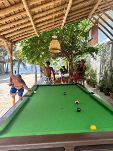 un groupe d'hommes jouant au billard dans l'établissement Bamboo House Beach Lodge & Restaurant, à Puerto Galera