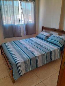 ein Bett mit gestreifter Decke in einem Schlafzimmer in der Unterkunft Bem estar in Aparecida