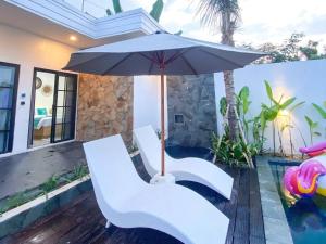 een patio met 2 witte stoelen en een parasol bij Ubu Villa Prambanan - 3 Bedrooms Villa near Prambanan Temple in Prambanan