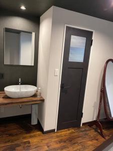 a bathroom with a sink and a black door at 壇ノ浦ハウス in Shimonoseki