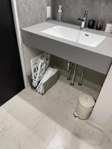 a bathroom with a white sink and a white tile floor at 壇ノ浦ハウス in Shimonoseki